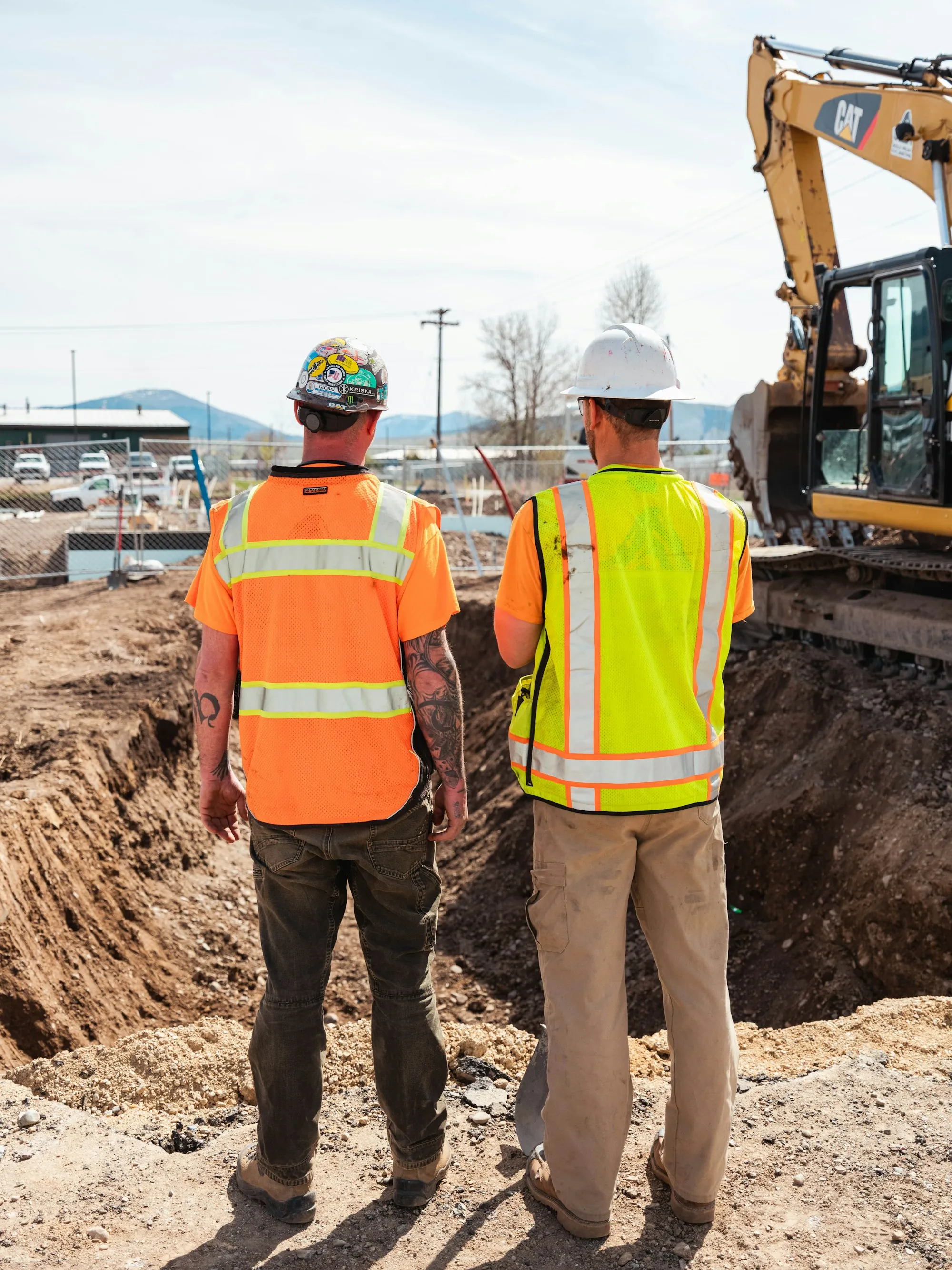 Two workers in hi-vis vests at an excavation